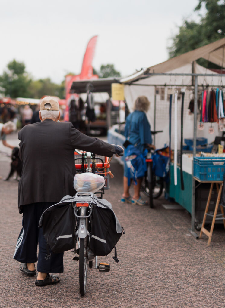 Een man met een fiets op een marktplein