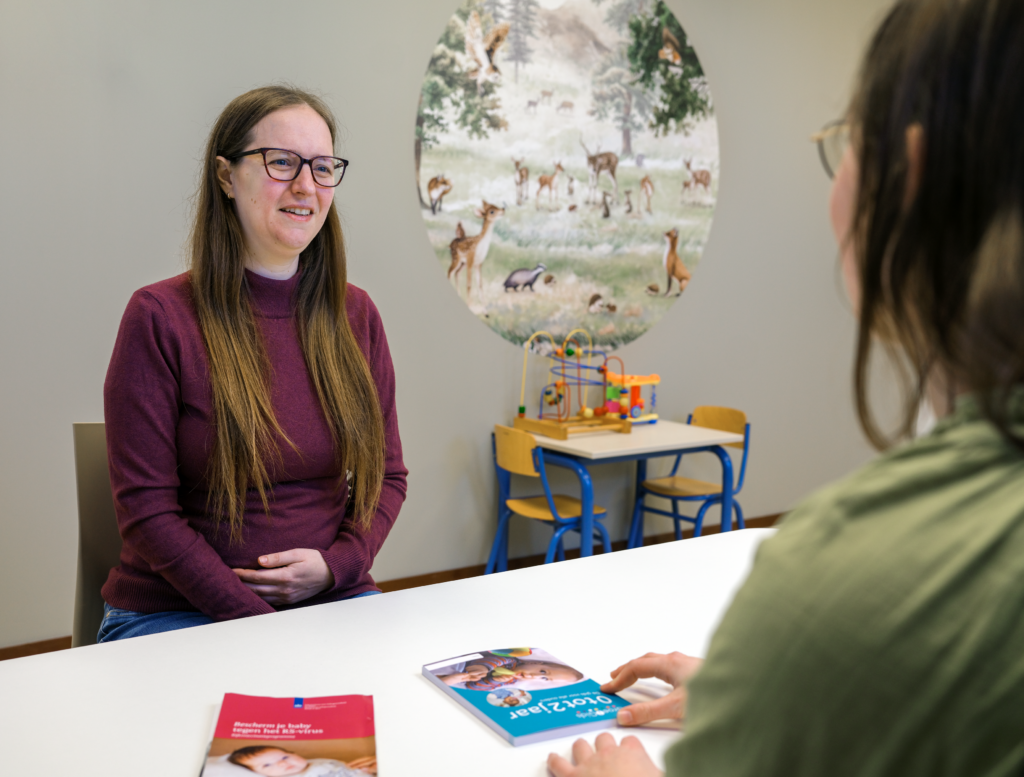 Zwangere vrouw in gesprek met de jeugdverpleegkundige op het consultatiebureau.